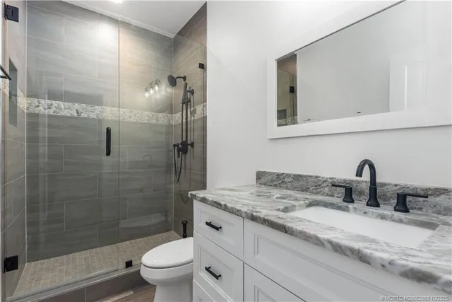 a bathroom with a granite countertop sink a toilet and a mirror