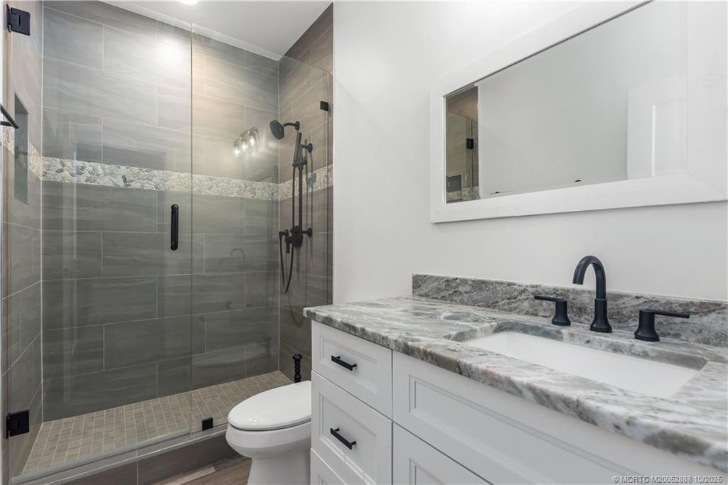 13468 Northwest Harbour Ridge Boulevard, Unit 2A Palm City, FL 34990 - Photo 26 of 38 a bathroom with a granite countertop sink a toilet and a mirror