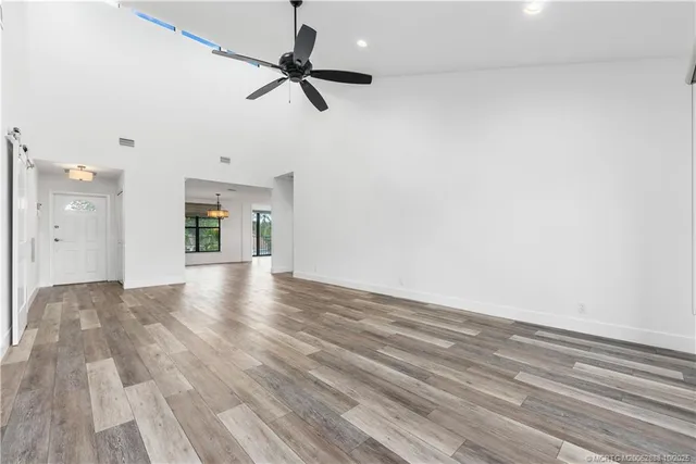 a view of empty room with wooden floor and fan