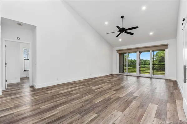 a view of empty room with wooden floor and fan