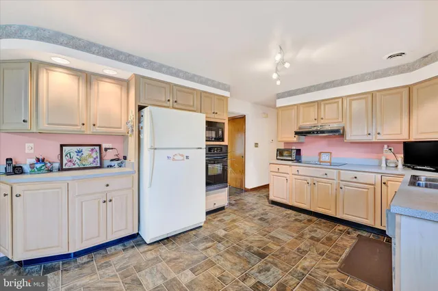 a kitchen with granite countertop a refrigerator stove top oven and sink