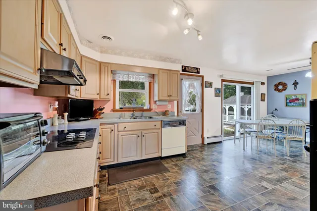 a kitchen with stainless steel appliances granite countertop a stove top oven a sink a dining table and chairs with wooden floor