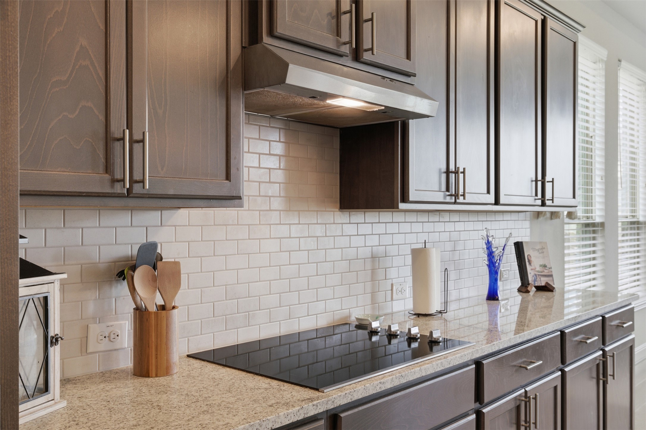 118 Bear Paw Run Georgetown, TX 78628 - Photo 12 of 35 The kitchen features dark wood cabinetry, a light-colored granite countertop, and a white subway tile backsplash