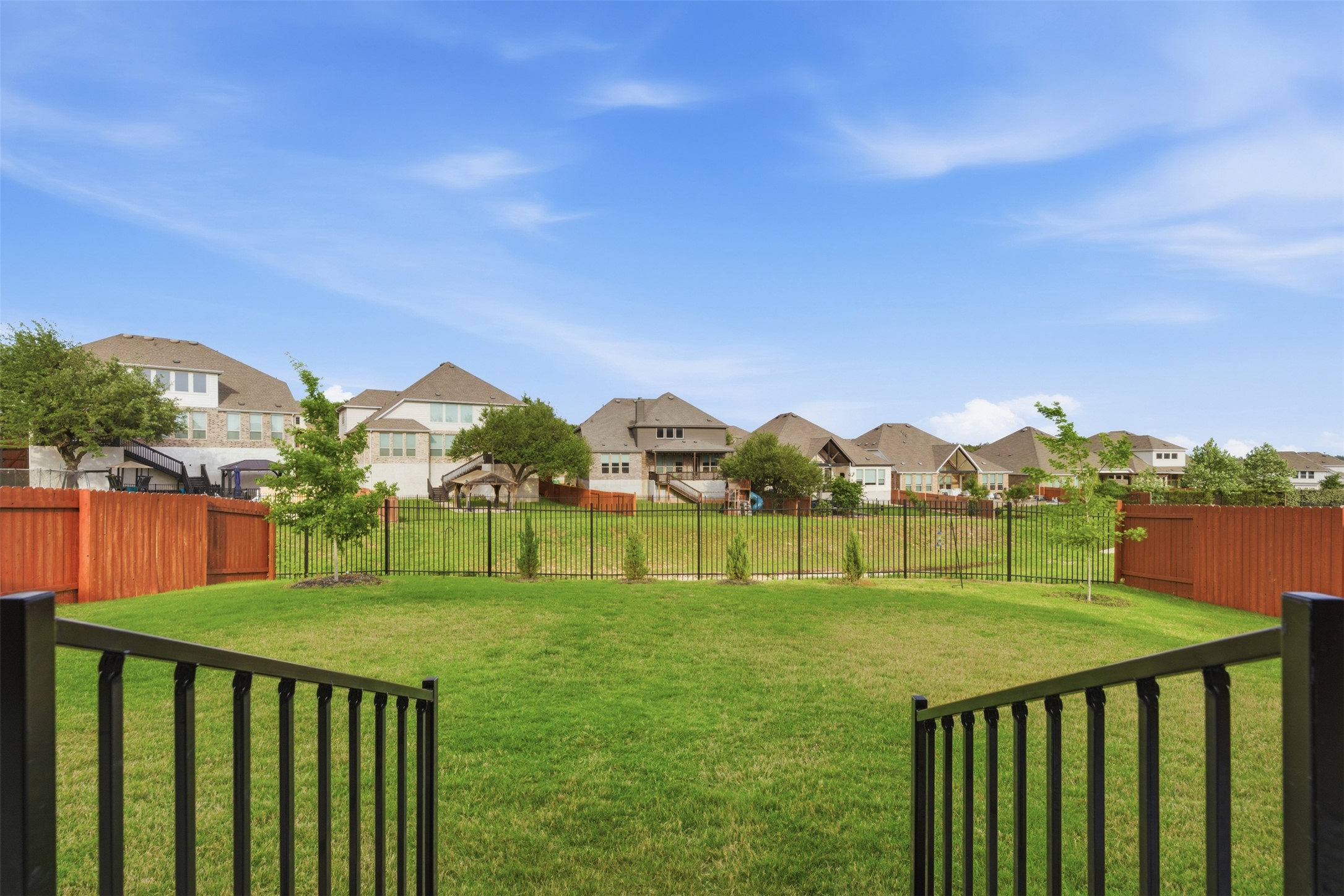 118 Bear Paw Run Georgetown, TX 78628 - Photo 25 of 35 The property features a spacious lawn, enclosed by a black metal fence and a brown privacy fence, with several young trees