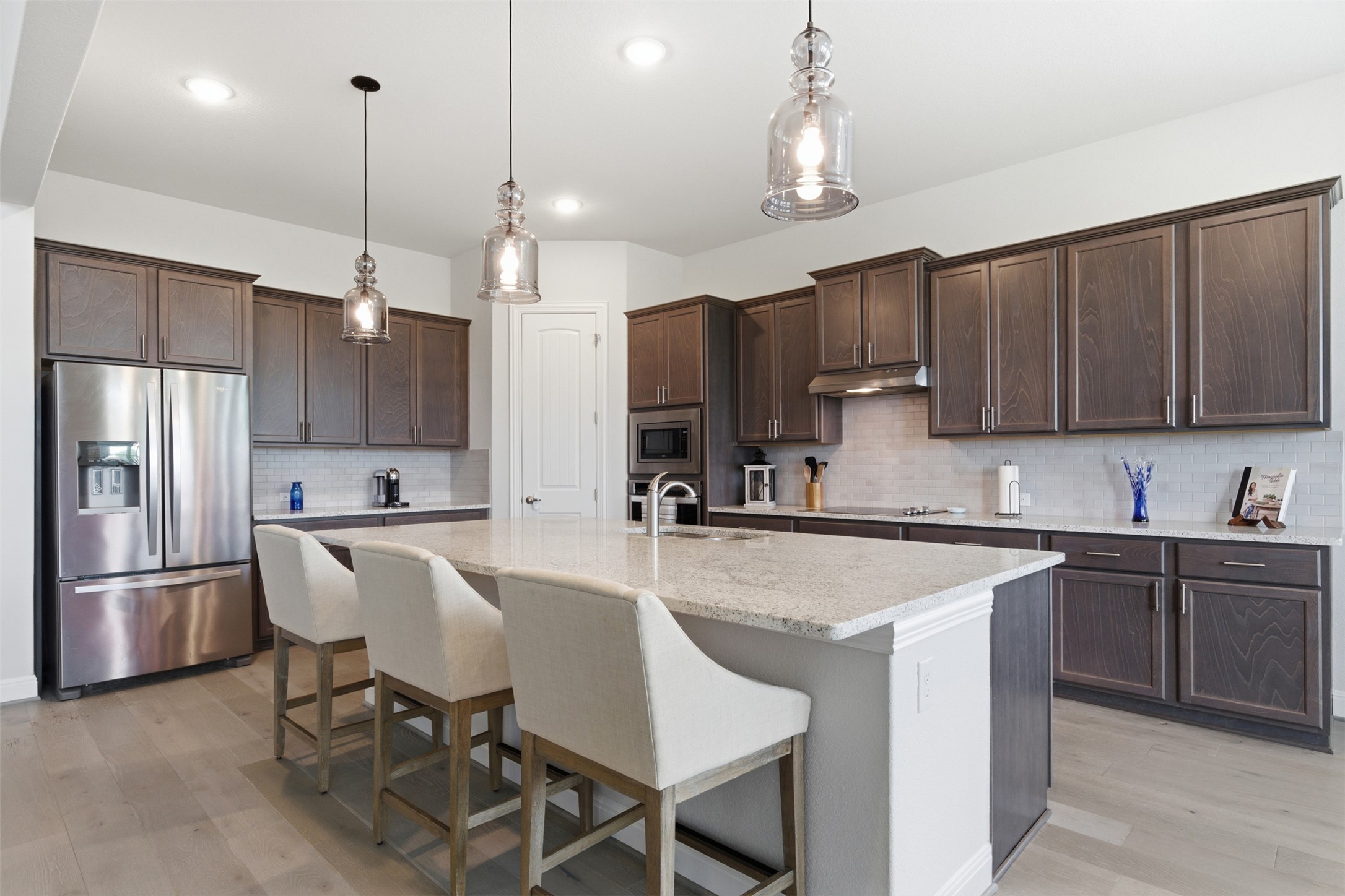 118 Bear Paw Run Georgetown, TX 78628 - Photo 9 of 35 The kitchen features dark wood cabinetry, a large center island with a light-colored countertop, and stainless steel appliances