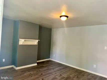 an empty room with wooden floor and bathroom