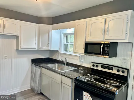 a kitchen with white cabinets a sink and stainless steel appliances