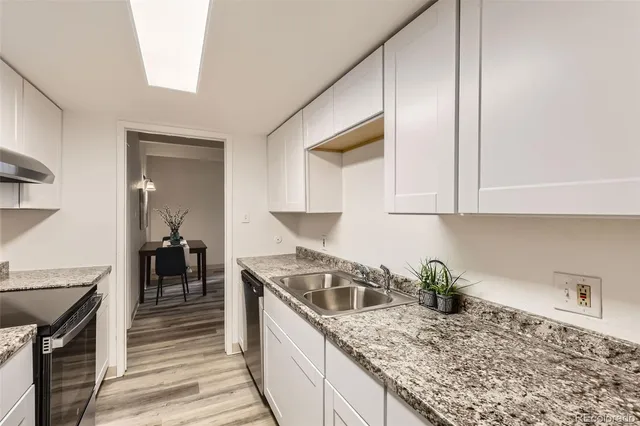 a kitchen with granite countertop a sink a stove and cabinets
