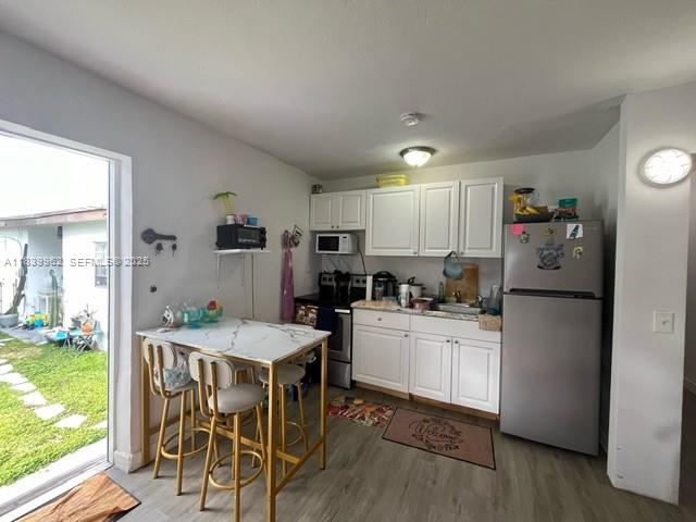 7230 Northwest 3rd Street Miami, FL 33126 - Photo 9 of 28 a kitchen with a refrigerator a dining table and chairs