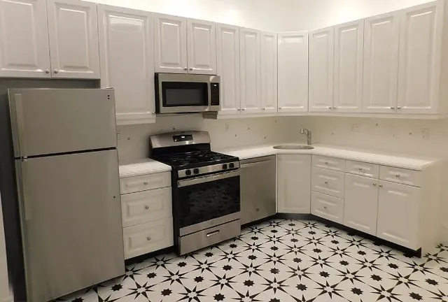 a kitchen with white cabinets and appliances