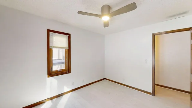 an empty room with windows and ceiling fan