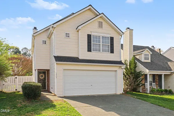 a view of a white house with a small yard and large tree