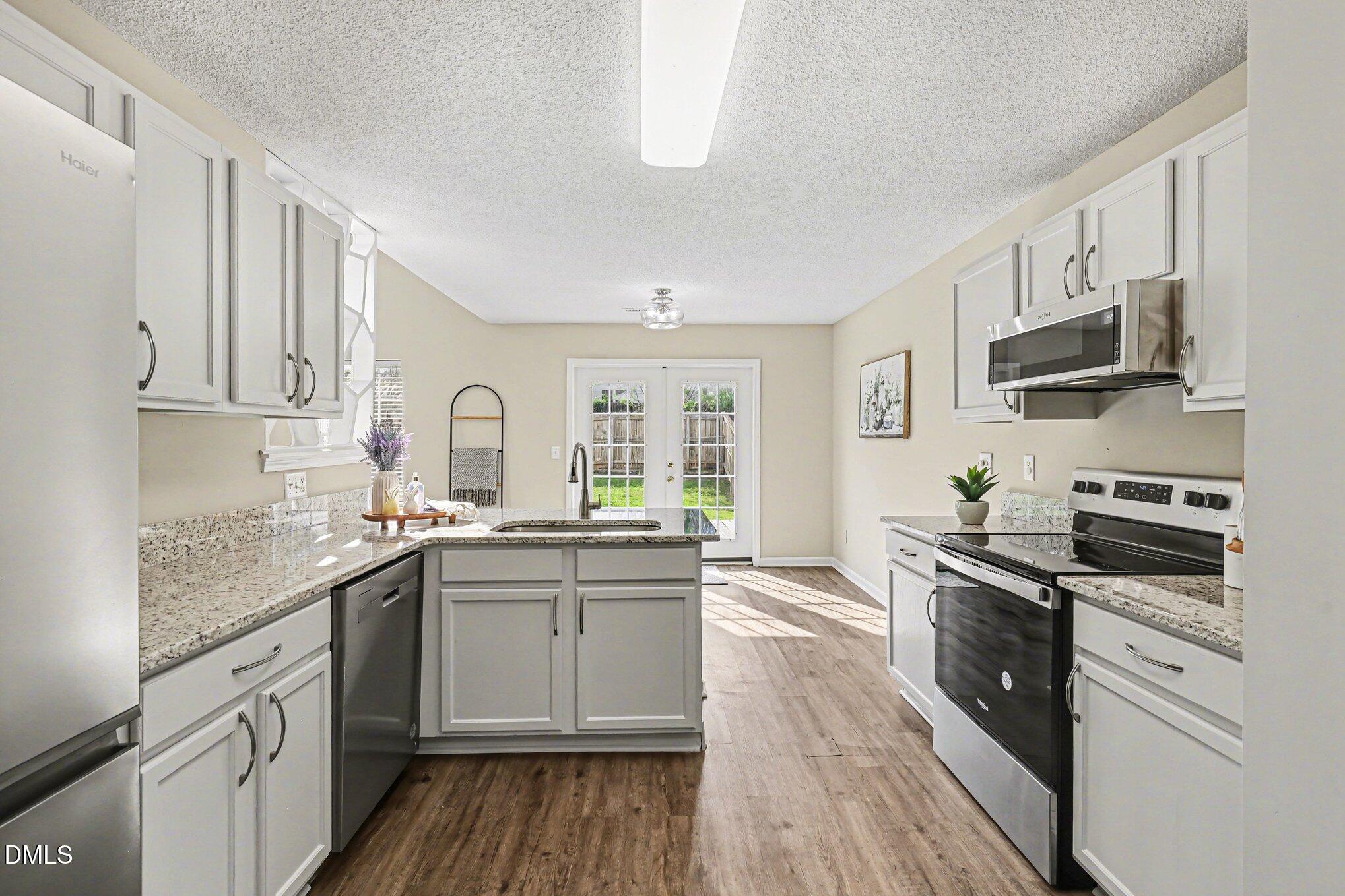 9904 Treymore Drive Raleigh, NC 27617 - Photo 10 of 33 a kitchen with stainless steel appliances granite countertop a stove top oven a sink dishwasher and white cabinets with wooden floor