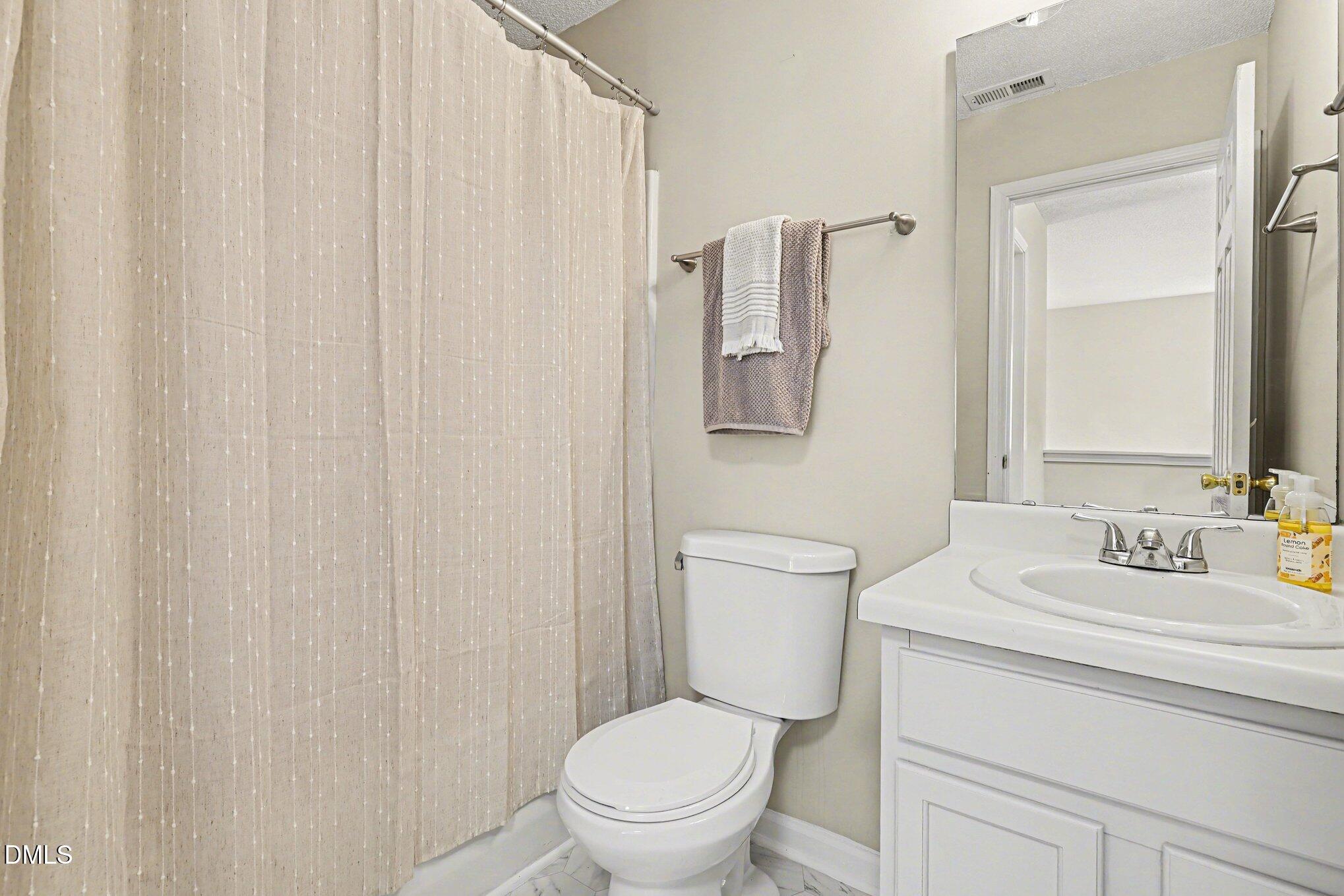 9904 Treymore Drive Raleigh, NC 27617 - Photo 20 of 33 a bathroom with a toilet a sink and a mirror