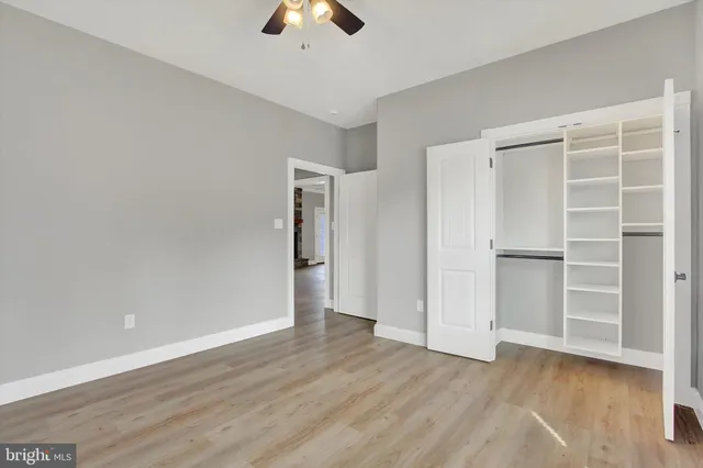 an empty room with wooden floor fan and windows