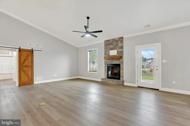a view of an empty room with wooden floor fireplace and a window