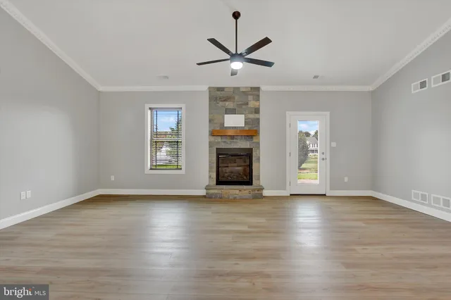 a view of an empty room with wooden floor fireplace and a window