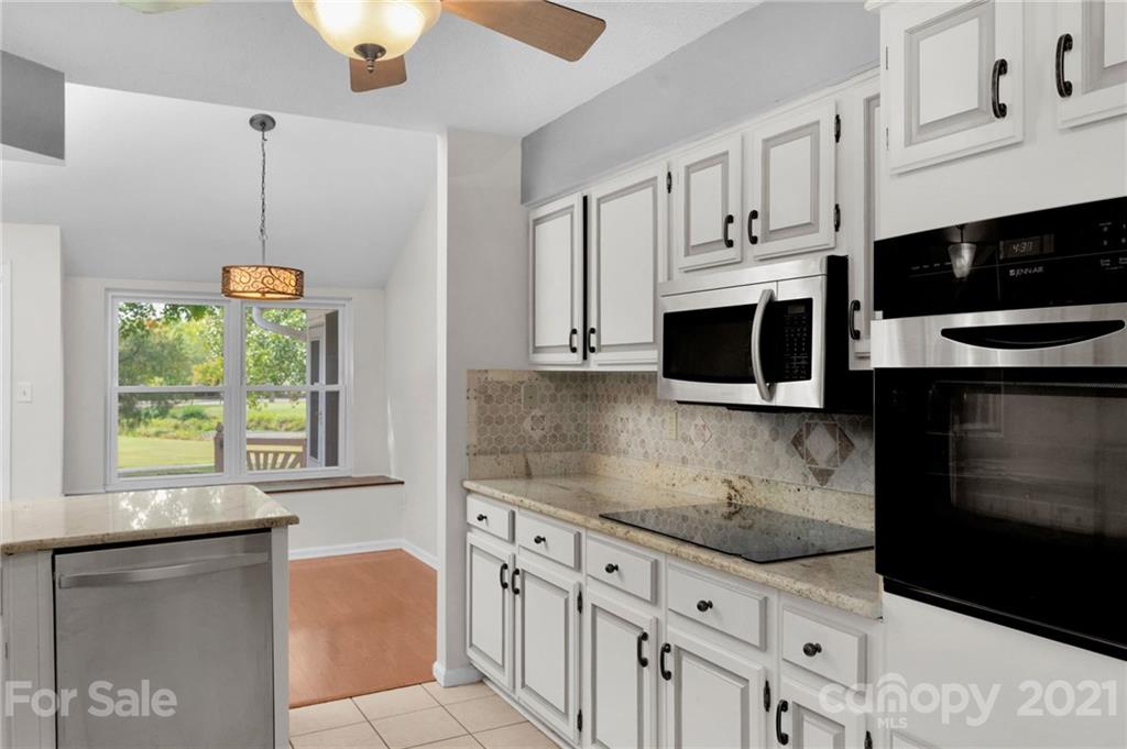 9838 Fairway Ridge Road, Unit 11 Charlotte, NC 28277 - Photo 20 of 40 a kitchen with stainless steel appliances kitchen island granite countertop a stove a microwave and a sink