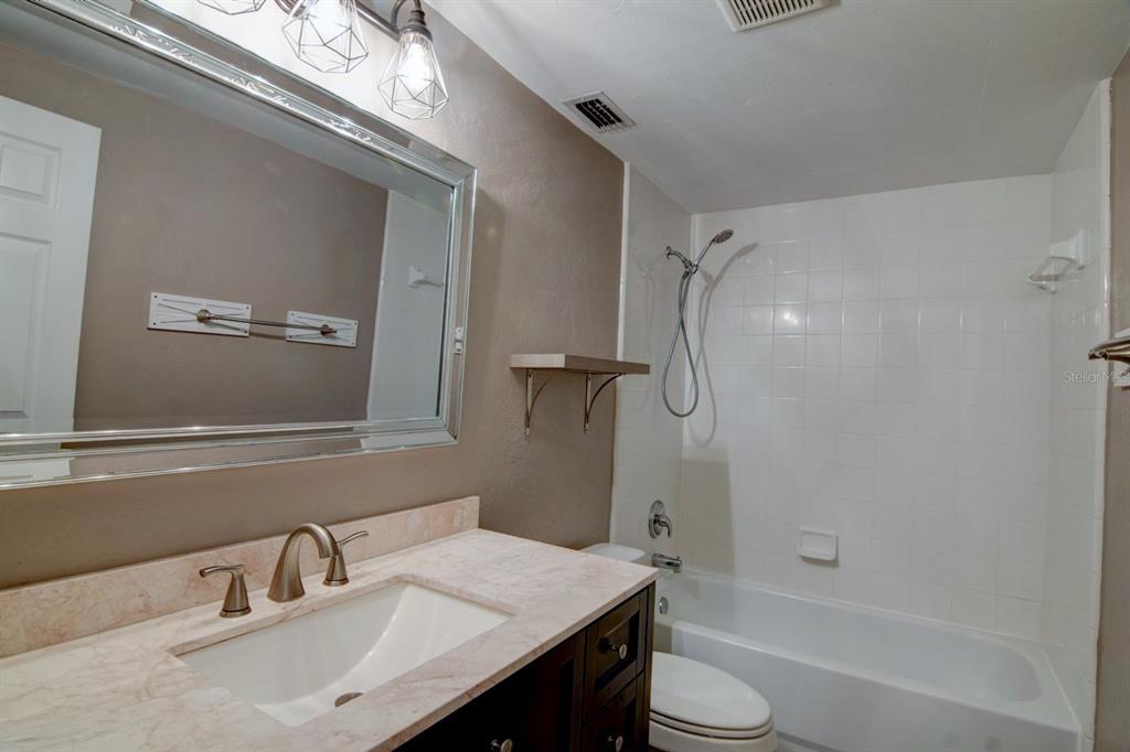 4933 Northwest 1st Place, Unit 110 Gainesville, FL 32607 - Photo 20 of 31 a bathroom with a granite countertop sink toilet and shower