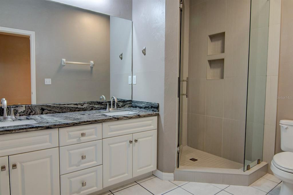 4933 Northwest 1st Place, Unit 110 Gainesville, FL 32607 - Photo 21 of 31 a bathroom with a granite countertop sink a mirror and a shower