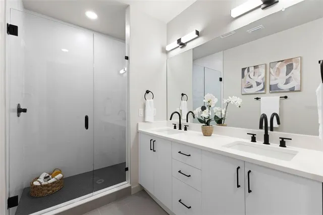 a bathroom with a double vanity sink mirror and shower