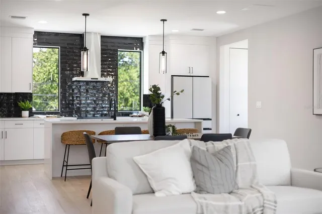 a living room with large couches chandelier and a large window