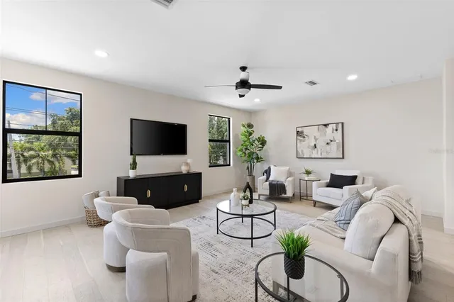 a living room with furniture a flat screen tv and a large window