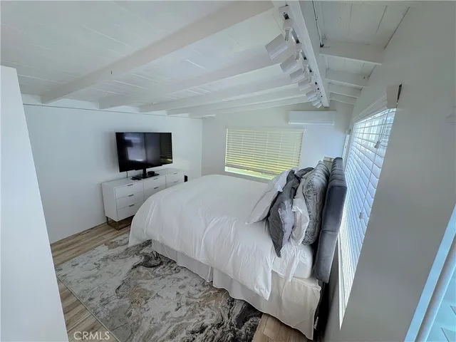 a bedroom with a bed and flat tv screen on the dresser