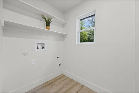 a view of hallway with window and wooden floor