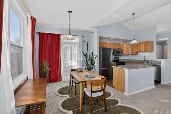 a kitchen with stainless steel appliances granite countertop a stove a sink a refrigerator a microwave a dining table and chairs
