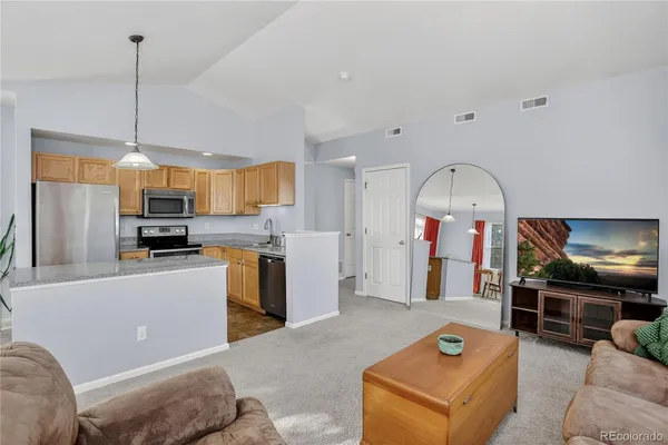 a living room with stainless steel appliances kitchen island granite countertop a refrigerator a stove top oven a sink and a dining table with the view