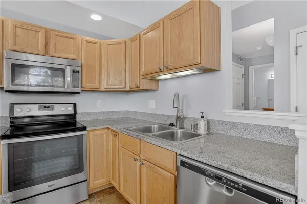 a kitchen with granite countertop white cabinets sink and stainless steel appliances