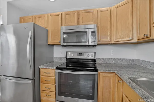 a kitchen with granite countertop white cabinets and stainless steel appliances