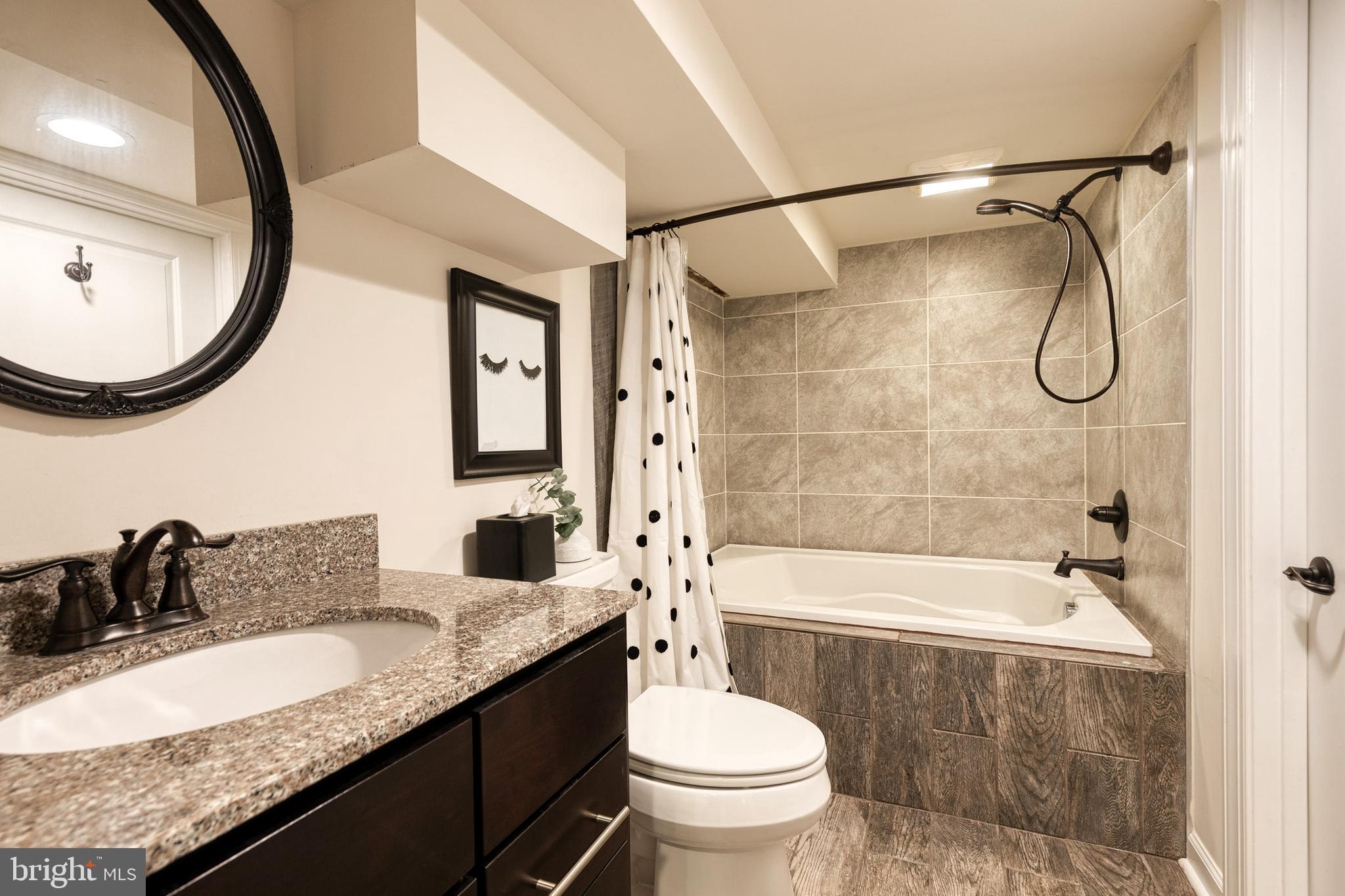 6504 Maplewood Road Baltimore, MD 21212 - Photo 32 of 45 a bathroom with a granite countertop sink a toilet and a mirror