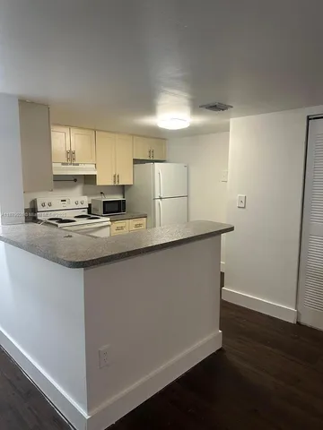 a kitchen with stainless steel appliances granite countertop a sink a stove a refrigerator a microwave and white cabinets