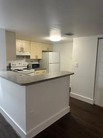 a kitchen with stainless steel appliances granite countertop a sink a stove a refrigerator a microwave and white cabinets