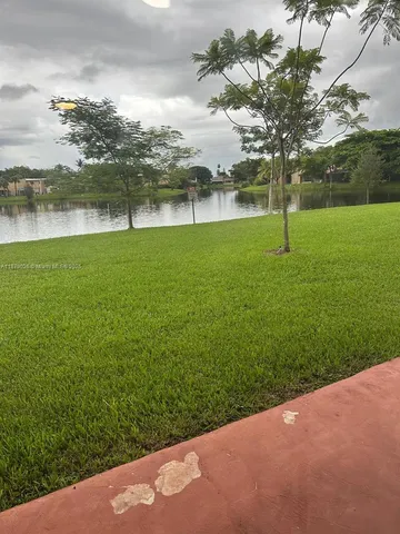 a view of a lake with a big yard and potted plants