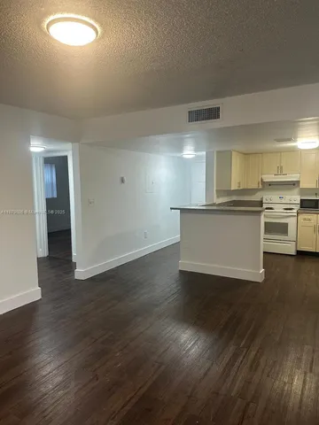 a view of a kitchen with a stove wooden cabinets and a refrigerator