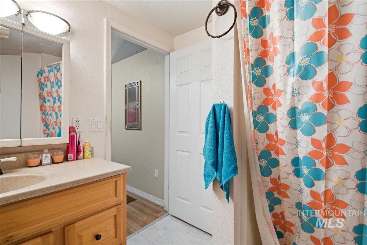 3929-3927 Homestead Road Homedale, ID 83628 - Photo 16 of 45 Bathroom featuring a wood-finish vanity with an integrated sink and light-toned countertop, a surface-mounted medicine cabinet with integrated lighting, and a white paneled door