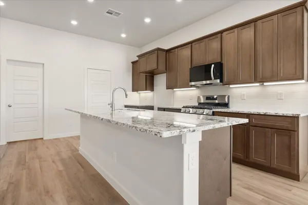 a kitchen with stainless steel appliances granite countertop a sink a stove and a microwave oven with cabinets