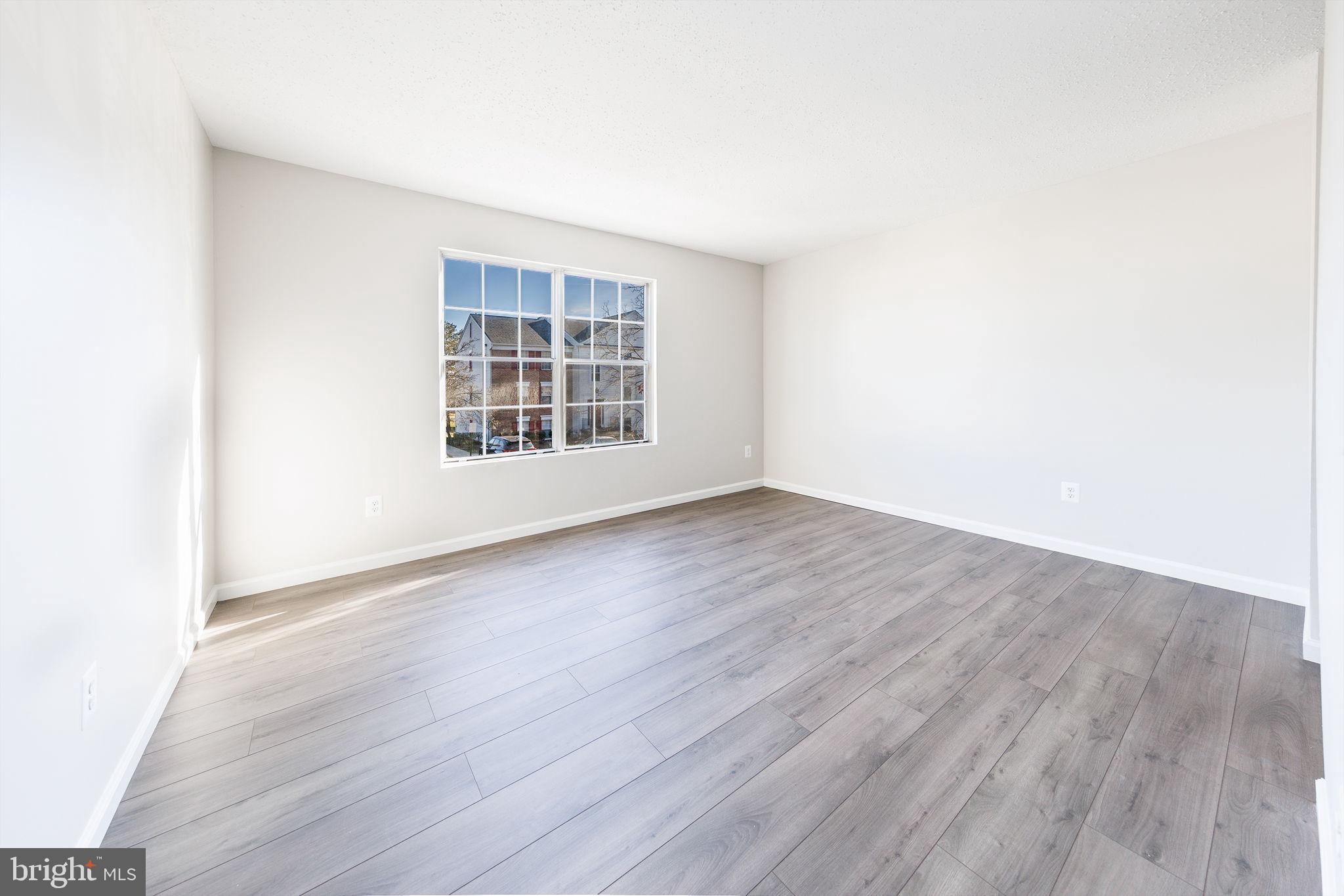 118 Fort Evans Road Southeast, Unit C Leesburg, VA 20175 - Photo 18 of 35 an empty room with wooden floor and windows