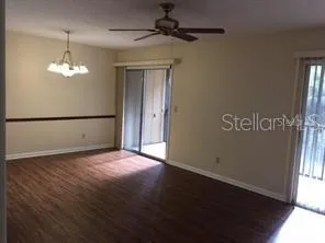 an empty room with chandelier fan and windows