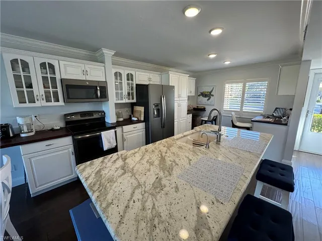 a large kitchen with kitchen island a stove a sink a refrigerator a stove a dining table and chairs