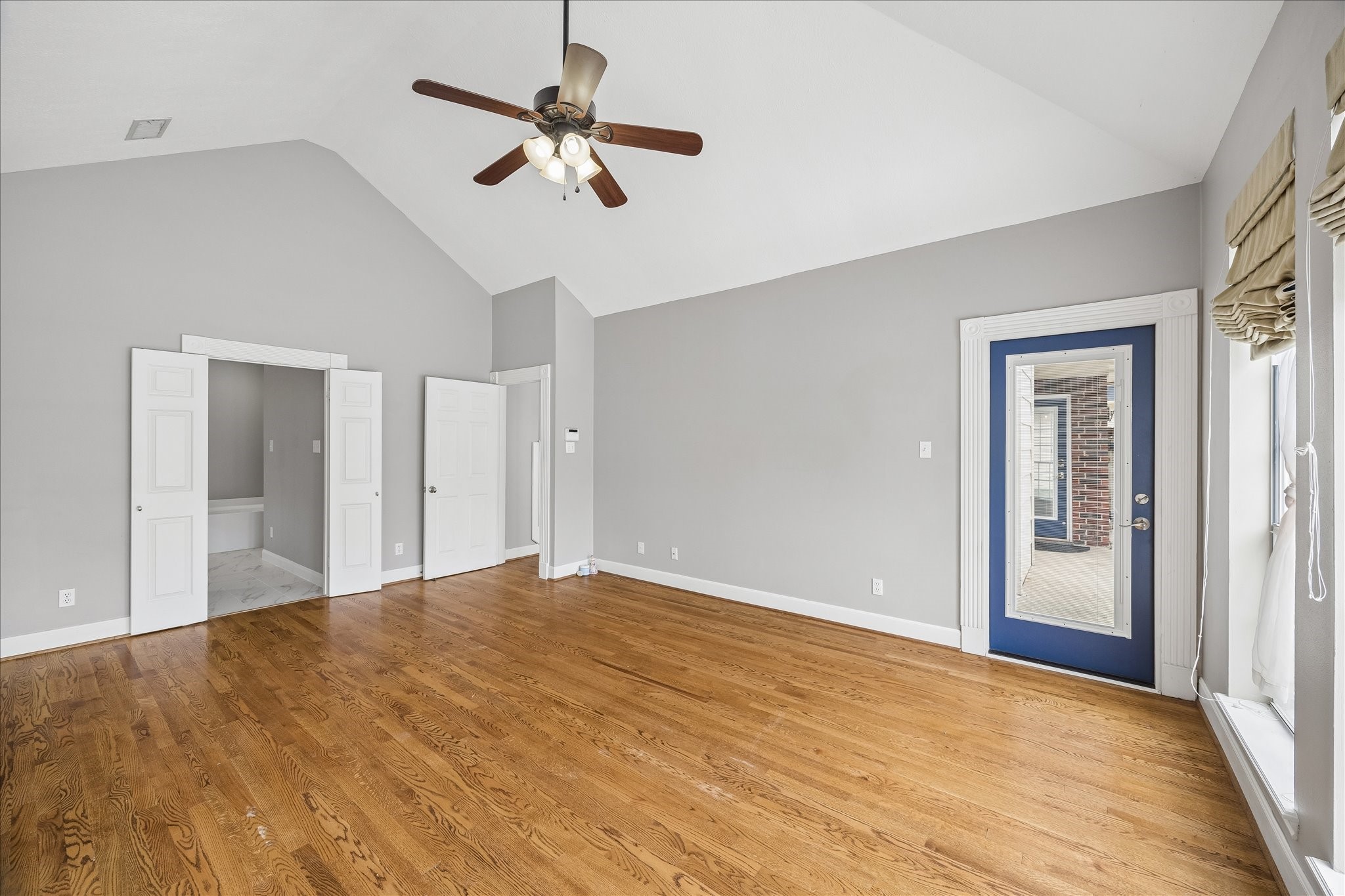 7915 Huddersfield Court Spring, TX 77379 - Photo 20 of 37 Alternate view of the first-floor primary suite showing the vaulted ceiling, hardwood floors, updated bath access, and private door leading to the backyard.