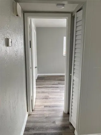 a view of a hallway with wooden floor and closet