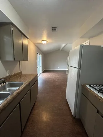 a kitchen with granite countertop a refrigerator and a sink