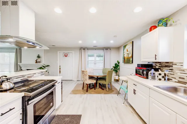 a large white kitchen with stainless steel appliances granite countertop a stove and a sink