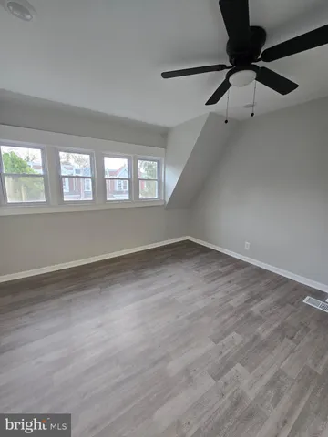 an empty room with wooden floor fan and windows