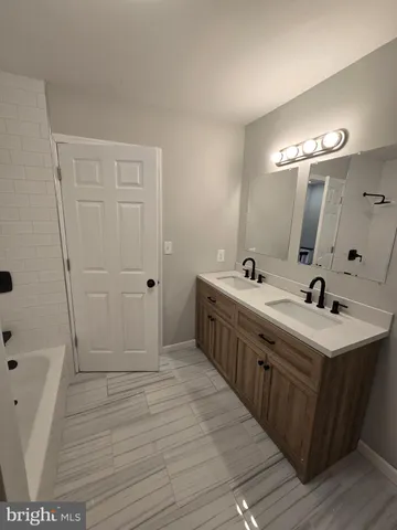 a spacious bathroom with a double vanity sink a mirror and a shower