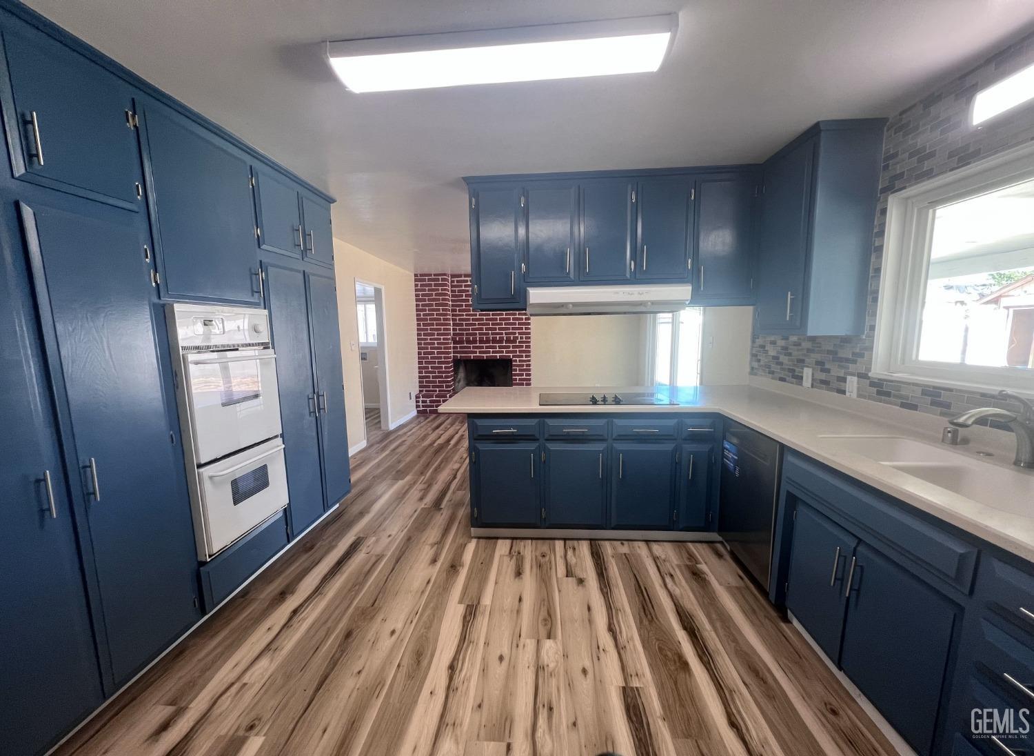Undisclosed Address Buttonwillow, CA 93206 - Photo 13 of 24 a kitchen with kitchen island wooden floors wooden cabinets a sink and a window